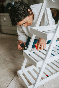 Mid adult woman adjusting shelf at home