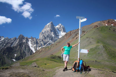 Woman standing by information sign against mountains