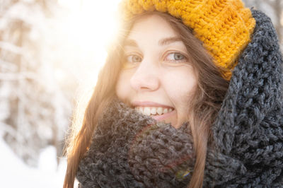 Portrait of a smiling young caucasian woman in a bright woolen hat and scarf, against the backdrop