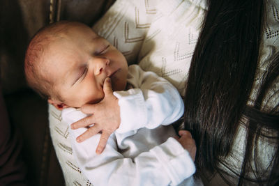 Close-up of mother carrying cute sleeping daughter at home