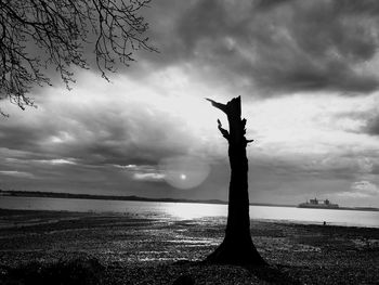 Silhouette of man on beach against dramatic sky