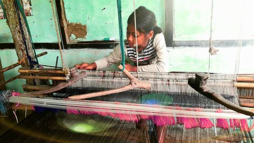 Girl weaving loom in workshop