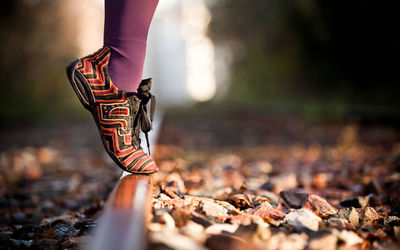 Low section of woman tiptoeing on railroad track