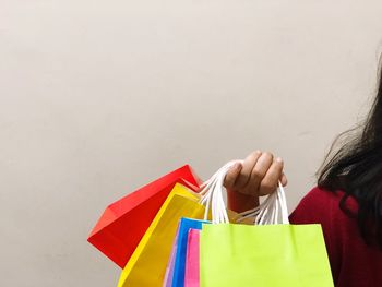 Close-up of woman multi colored shopping bags over white background