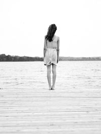 Rear view of young woman standing against sea