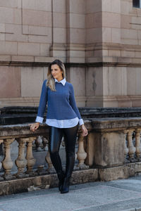 Woman looking away while standing against building