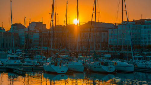 Boats moored at harbor against sky during sunset