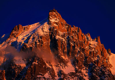 Low angle view of illuminated mountain against blue sky