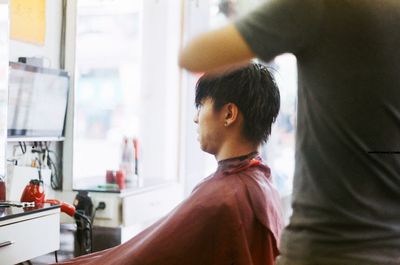 Barber cutting man hair at salon