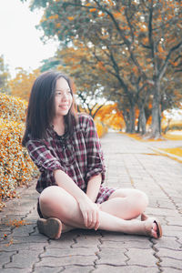 Portrait of a smiling young woman sitting on autumn leaves