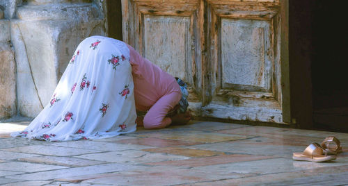 Woman sitting on wood outside building