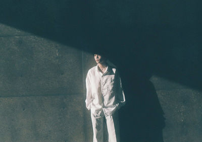 Young woman standing against wall