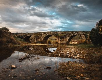 Arch bridge over river against sky