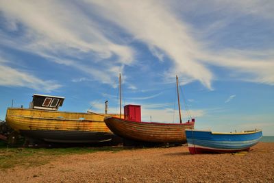 Three boats on beach against sky