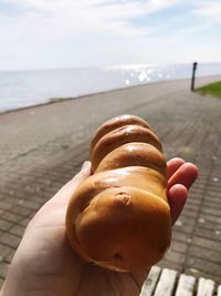 Close-up of hand holding ice cream against sky