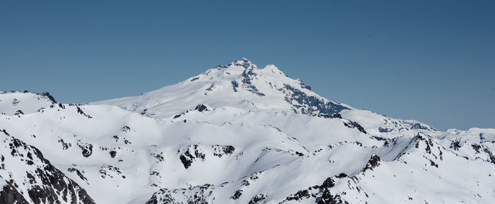 Scenic view of snow covered mountains against clear blue sky