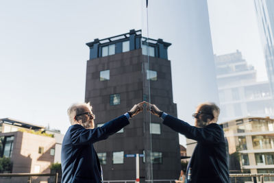 Senior businessman touching smart screen outside office building