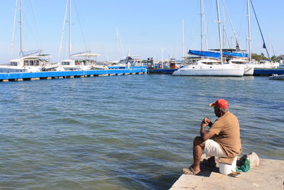Man sitting on sailboat by sea against sky