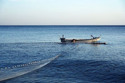 Fishing boat in sea against clear sky