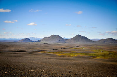 Scenic view of road by mountains against sky