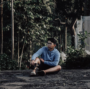 Young man sitting on plant in forest