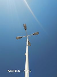 Low angle view of street lights against clear blue sky