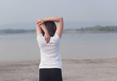 Rear view of woman standing in sea against sky