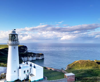 Lighthouse by sea against sky