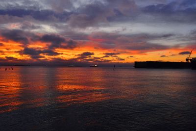 Scenic view of sea against dramatic sky during sunset