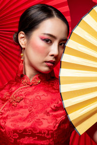 Close-up portrait of young woman holding hand fan