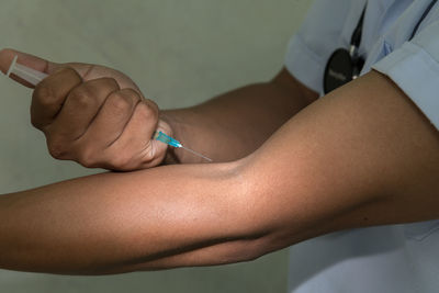 Midsection of doctor injecting arm