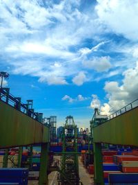 Cranes at harbor against cloudy sky