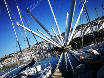 Sailboats moored on harbor against clear blue sky