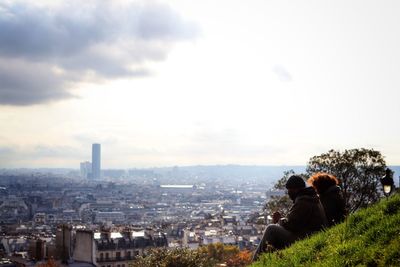 Rear view of couple in the cityscape of paris against sky