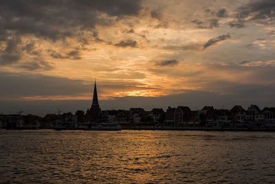 View of buildings by sea against sky during sunset