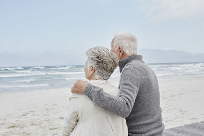 Senior couple standing on the beach with arms around