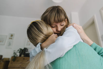 Depressed daughter embracing mother at home