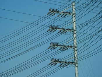 Low angle view of electricity pylon against clear sky