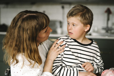 Mother talking with son having down syndrome at home