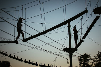 Low angle view of men working on bridge against sky