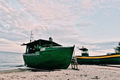 Boat moored on beach against sky during sunset