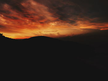 Scenic view of silhouette mountains against orange sky