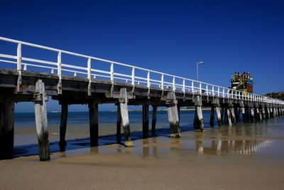 Bridge over sea against clear blue sky