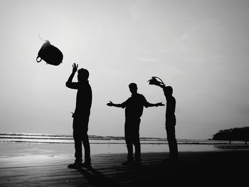 Silhouette people playing on beach against sky