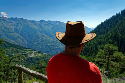 Rear view of man looking at mountains against sky