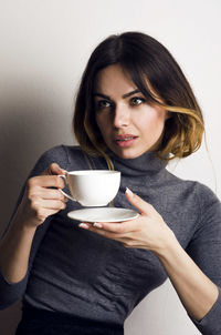 Portrait of woman holding coffee cup against white background