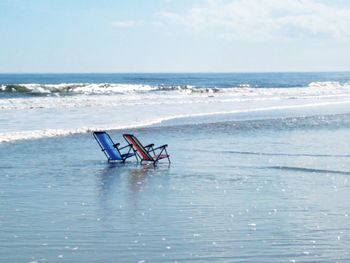 Lifeguard chair on beach against sky