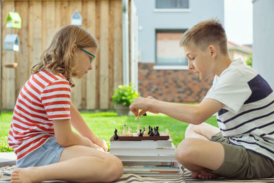 Rear view of siblings sitting on wall