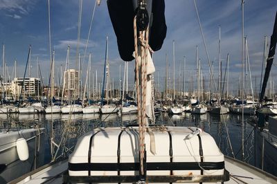 Sailboats moored in harbor against sky