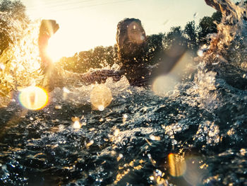 Multiple exposure of screaming man with water and trees against sky